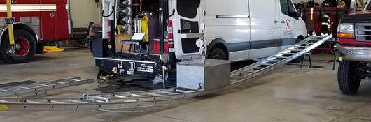 A ladder being tested bearing the weight of a heavy object in a fire department.